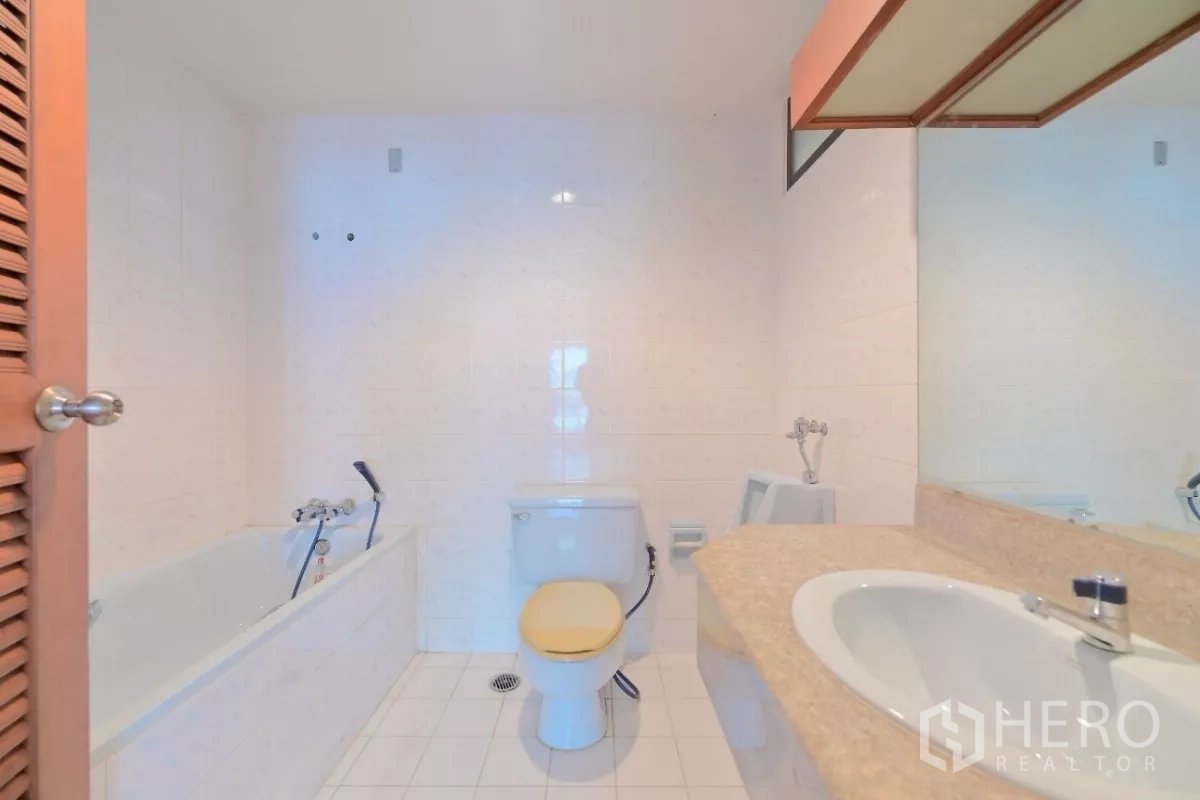 Townhouse for sale in Watthana, Bangkok - Bathroom with bathtub, toilet, stone countertop sink, and wall mirror.