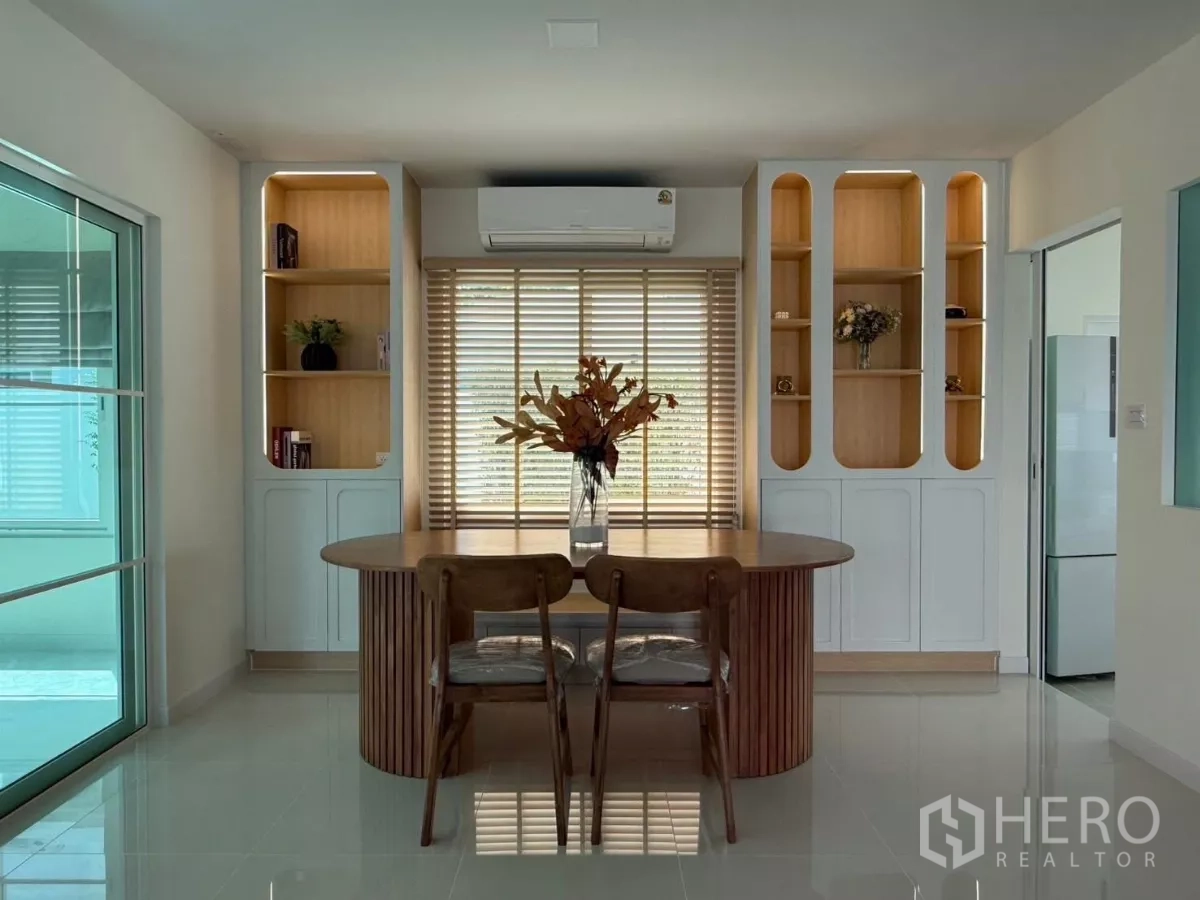 Detached House for rent in Bang Phli, Samut Prakan - Bright dining or home office with a round wooden table, built-in shelves, window blinds and air-conditioning beside a glass sliding door.