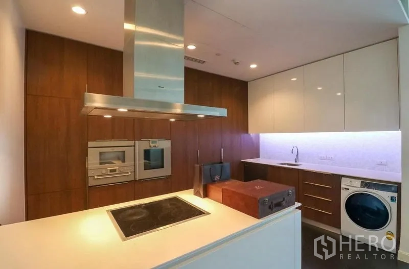 Condominium for rent in Pathum Wan, Bangkok - Contemporary kitchen with island cooktop, built-in ovens and a washer.