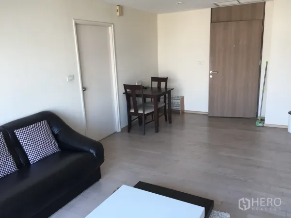 公寓 出租或出售在Khlong Toei, Bangkok - 宽敞起居区，黑色皮沙发与双人餐桌靠近入户门。