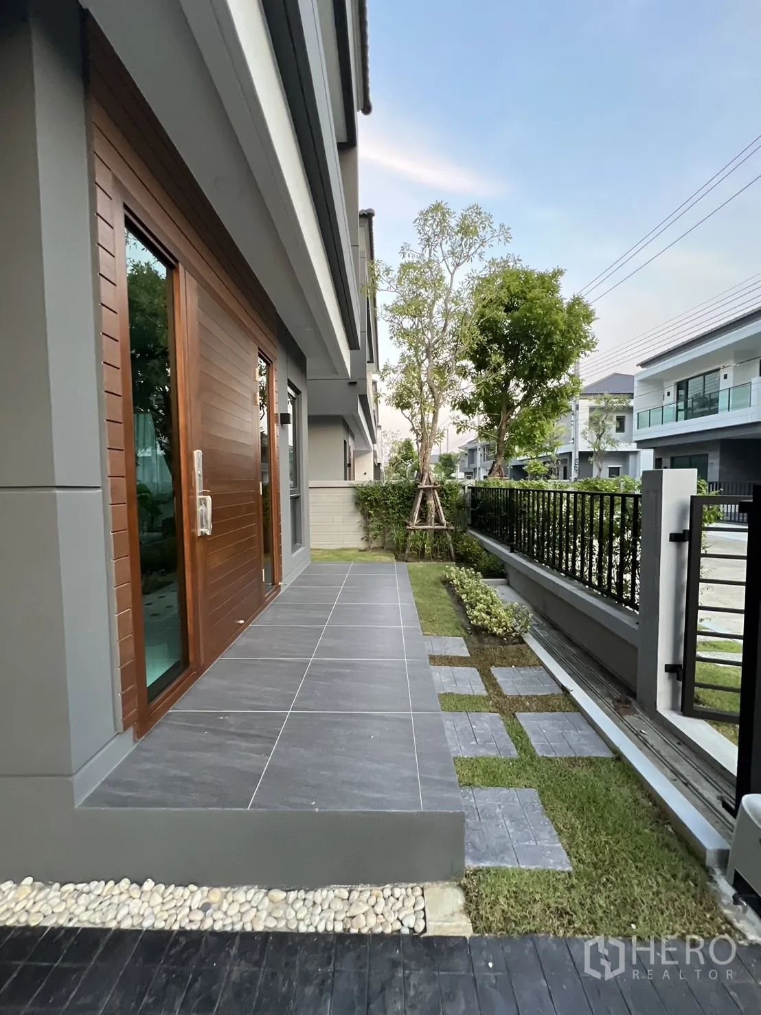 บ้าน ให้เช่าในBang Phli, Samut Prakan - เฉลียงหน้าบ้านปูกระเบื้องสีเทา พร้อมสวนหย่อมและรั้วเหล็ก