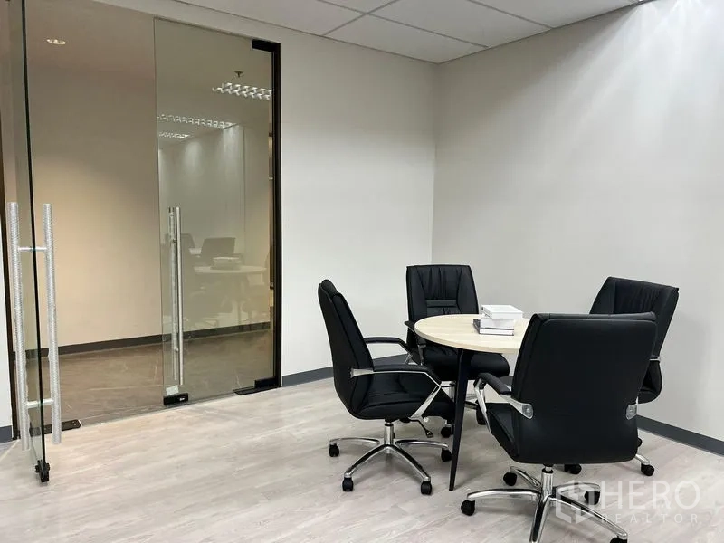 Office Space for rent in Sathon, Bangkok - Compact meeting corner with round table and four executive chairs beside a clear glass door.