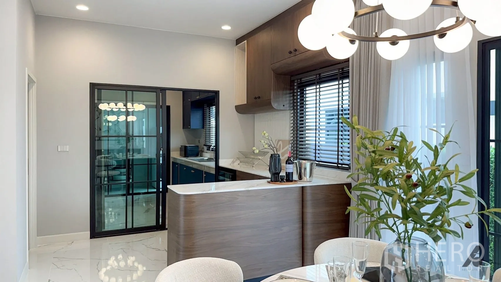 Detached House for rent in Bang Phli, Samut Prakan - Dining space with a round table, globe chandelier, marble-look floors, and a curved pantry bar.