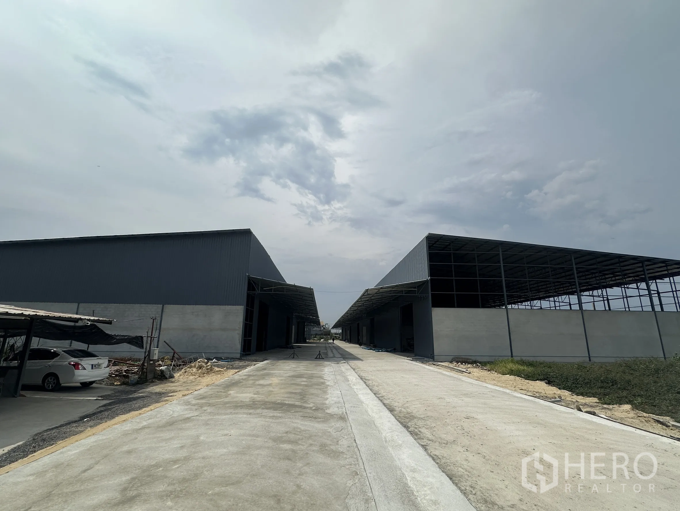 Warehouse for rent in Lam Luk Ka, Pathum Thani - Site view showing two warehouse blocks and a paved access road.