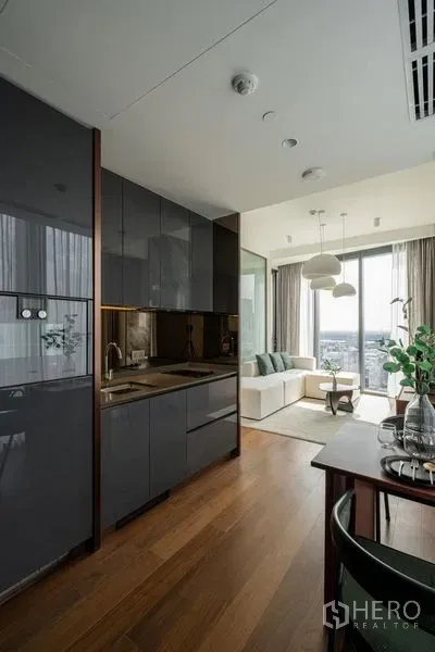 公寓 出租在Khlong Toei, Bangkok - 开放式厨房，亮面橱柜与木地板，连接餐桌与起居区。