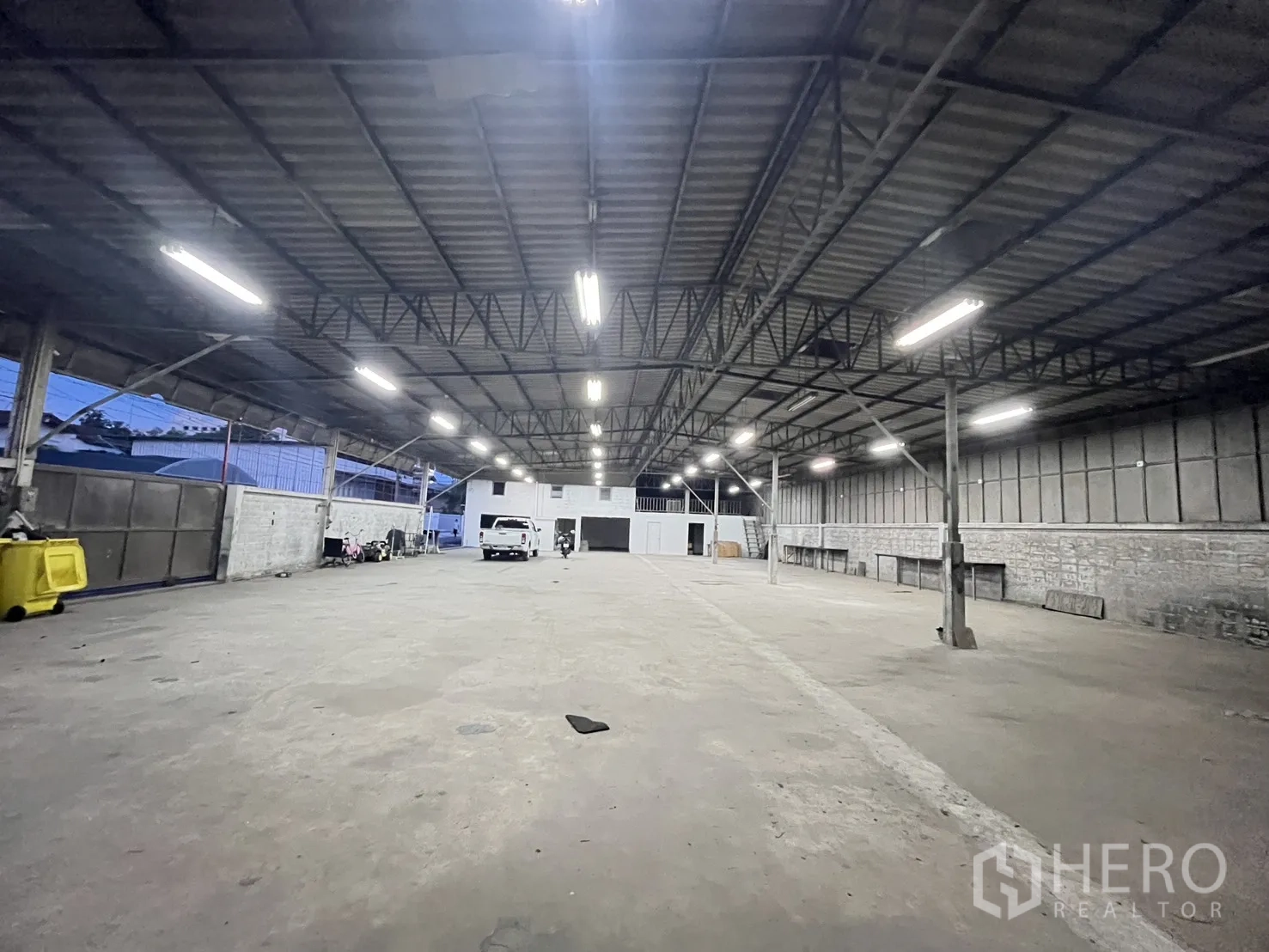 仓库 for rent in Chatuchak, Bangkok - 仓库内部宽阔空间，金属桁架屋顶与长条照明，混凝土地面。