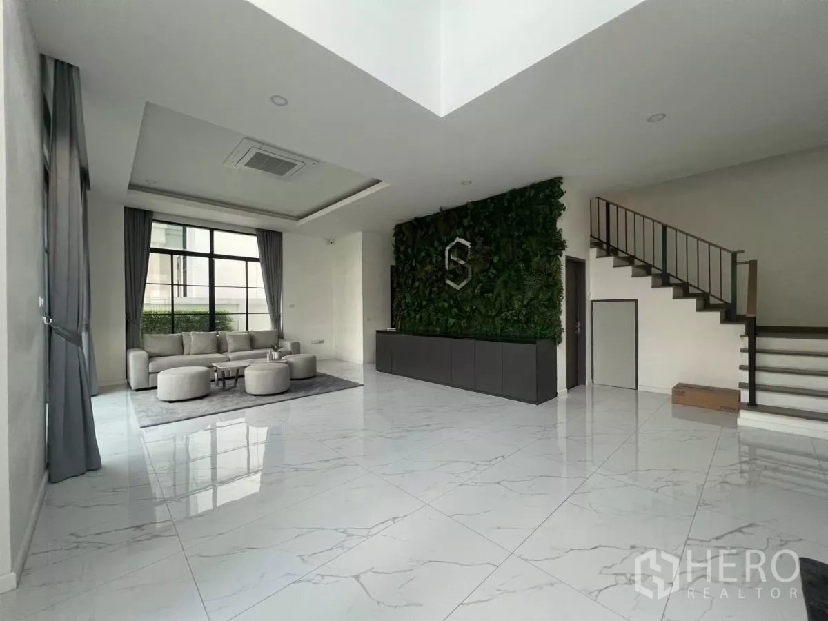 บ้าน ให้เช่าในLat Phrao, Bangkok - ห้องนั่งเล่นสว่าง พื้นลายหินอ่อน หน้าต่างบานใหญ่ ผนังสวนแนวตั้ง และบันไดสไตล์โมเดิร์นภายในบ้านเดี่ยว