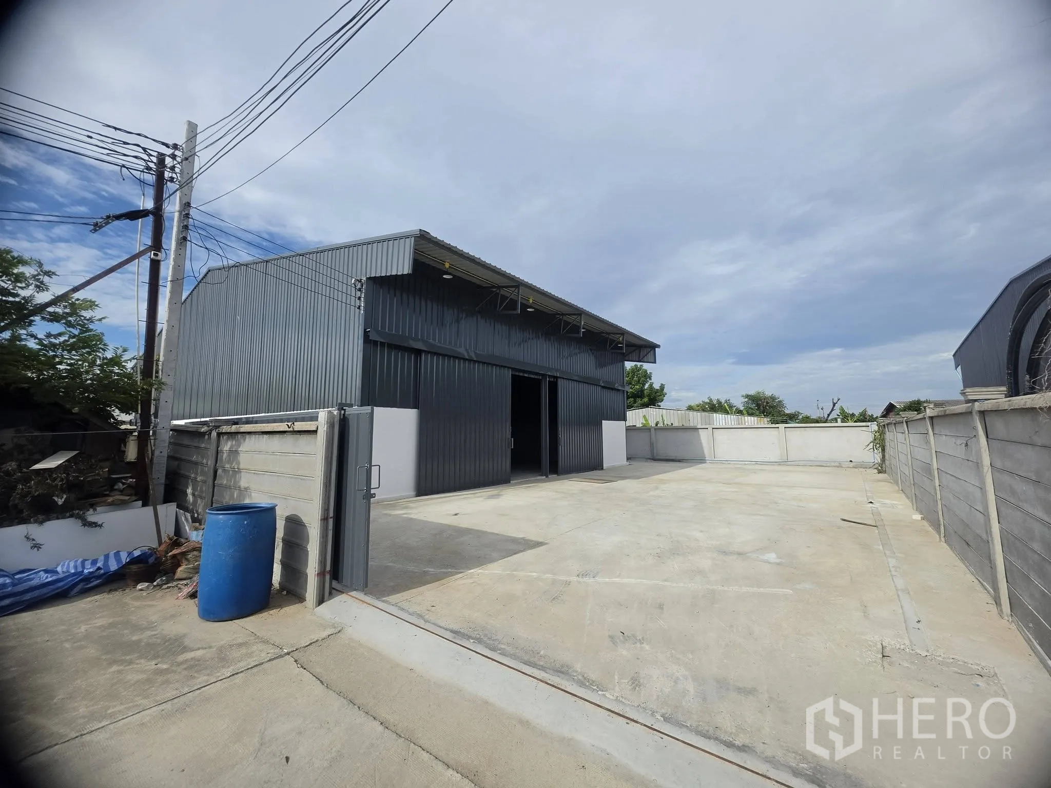 โกดัง for rent in Mueang Samut Prakan, Samut Prakan - ลานหน้าพร้อมพื้นคอนกรีตและตัวโกดังอยู่หลังกำแพงรั้วและประตูทางเข้า