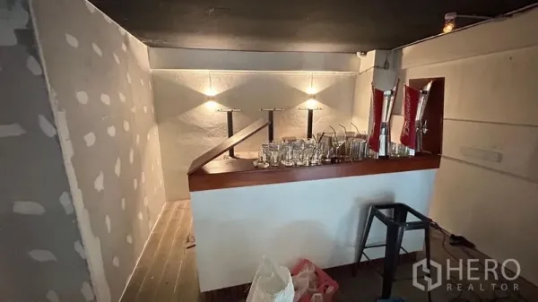 Shophouse for sale - Compact bar counter with glasses and beer taps in a small service room.