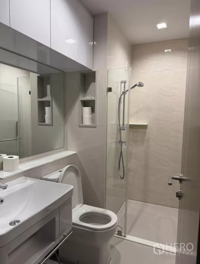 Condominium for rent in Chatuchak, Bangkok - Second bathroom with walk-in shower, white vanity, and built-in wall niches.
