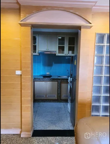 Condominium for rent in Ratchathewi, Bangkok - Separate kitchen with blue backsplash, cabinets and refrigerator.