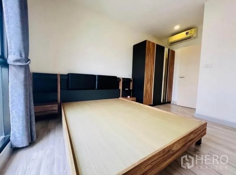 Townhouse for rent in Saphan Sung, Bangkok - Bedroom with platform bed frame, wood-tone wardrobe, air conditioner and floor-to-ceiling window.