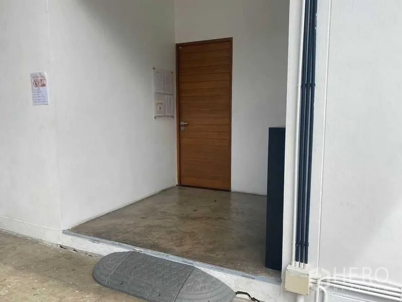 สำนักงานที่บ้าน ให้เช่าหรือขายในBang Khae, Bangkok - ทางเข้าอาคารด้านข้าง ประตูไม้และพื้นปูนขัดมัน