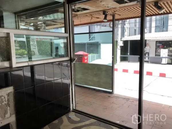 零售空间 出租在Khlong Toei, Bangkok - 入口区配滑动玻璃门与瓷砖墙，面向人行道。