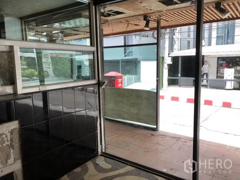 零售空间 出租在Khlong Toei, Bangkok - 入口区配滑动玻璃门与瓷砖墙，面向人行道。