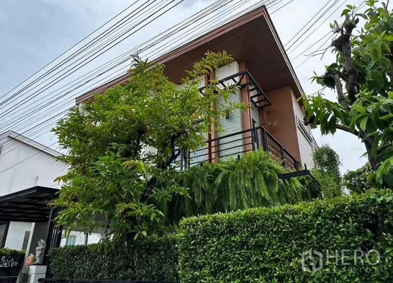 独立式住宅 出租在Prawet, Bangkok - 外立面一角，阳台与绿篱营造私密花园。