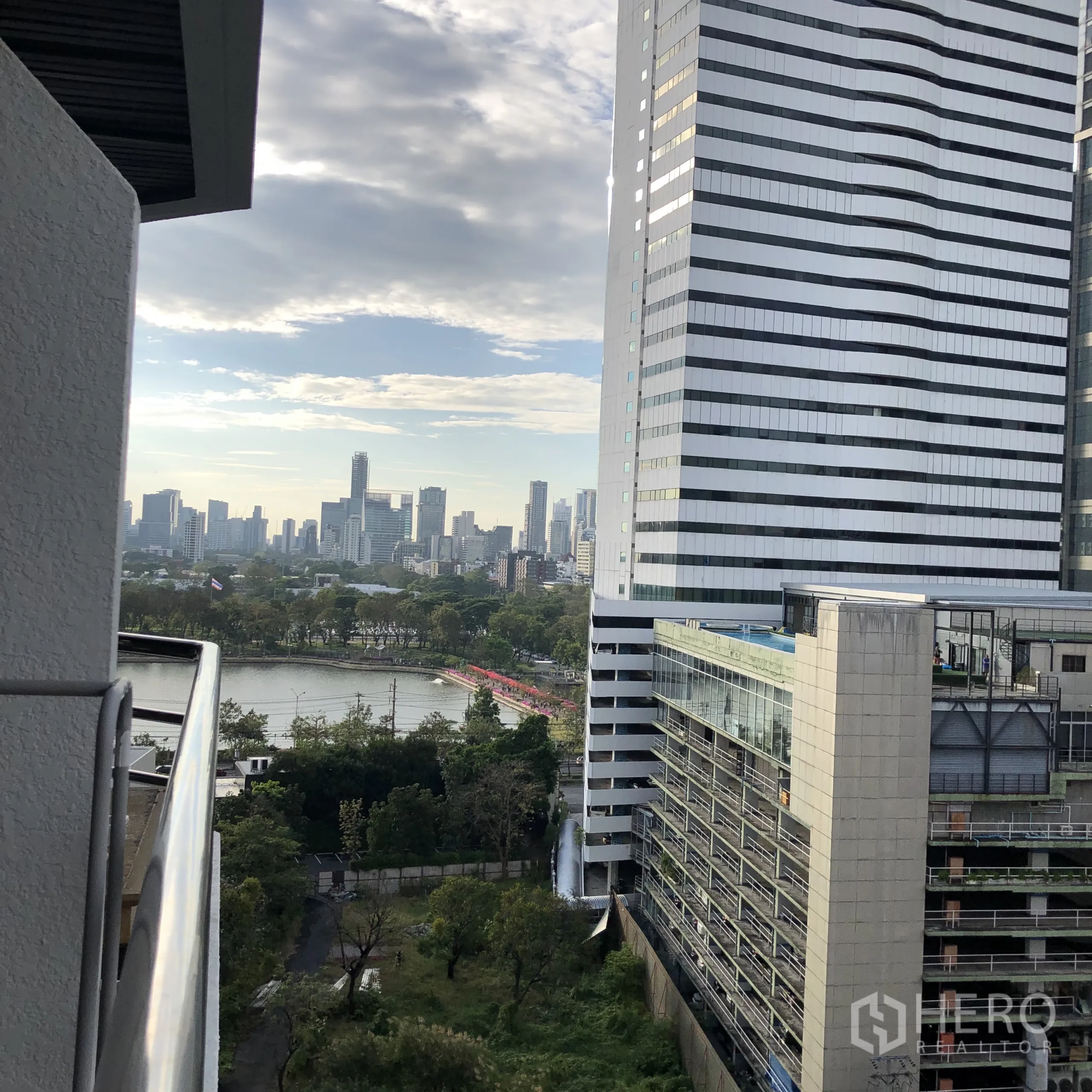 คอนโด ให้เช่าในKhlong Toei, Bangkok - ทิวทัศน์จากระเบียงไปยังสวนเบญจกิติและทะเลสาบ พร้อมอาคารสำนักงานสมัยใหม่
