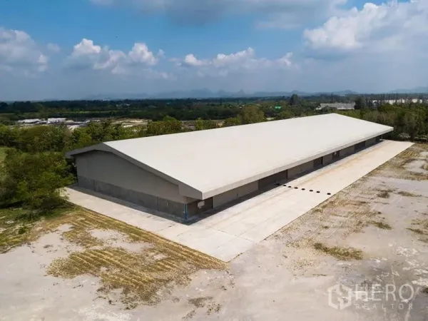 Warehouse for rent in Phra Phutthabat, Saraburi - Aerial view of a long single-story warehouse with a paved loading apron and green surroundings.