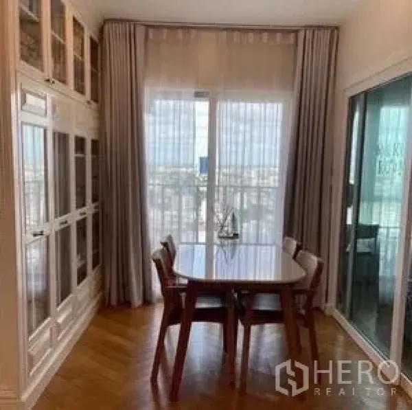 Condominium for rent or sale - Bright dining nook with wooden table for four, sheer curtains, and balcony city view through sliding glass doors.