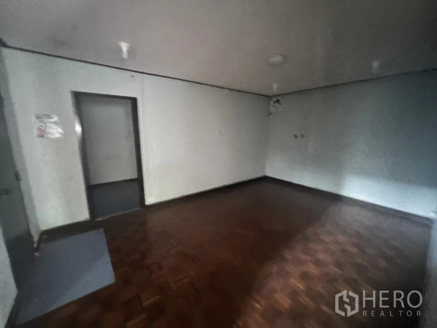 Home Office for rent in Watthana, Bangkok - Dim room with parquet flooring and plain painted walls.