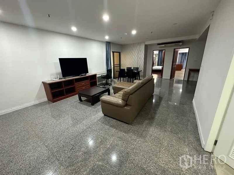 คอนโด ให้เช่าในWatthana, Bangkok - ห้องนั่งเล่นกว้าง โซฟาหนัง ชั้นวางทีวี ชุดโต๊ะทานข้าว และพื้นหินเงางาม