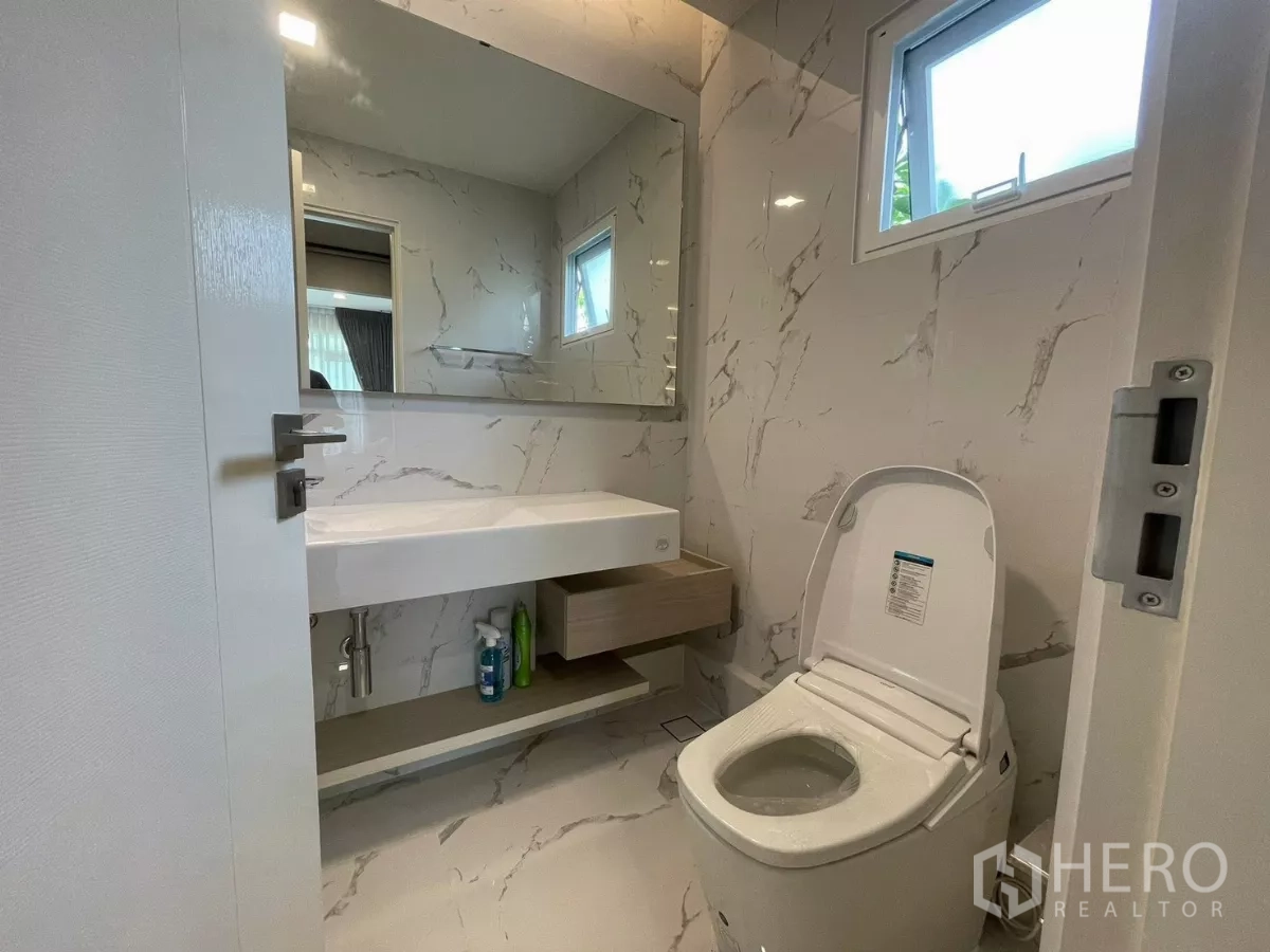 บ้าน ให้เช่าในPrawet, Bangkok - ห้องน้ำโมเดิร์น ผนังลายหินอ่อน กระจกบานใหญ่ เคาน์เตอร์และโถสุขภัณฑ์.