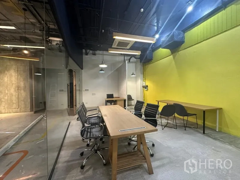 สำนักงาน ให้เช่า - ห้องประชุม โต๊ะไม้ เก้าอี้เมชสีดำ และท่อดักท์เปลือย