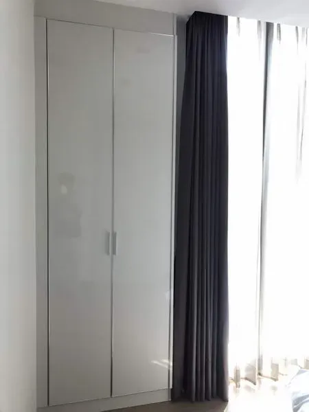 Condominium for rent or sale in Watthana, Bangkok - White built‑in wardrobe beside tall windows with blackout curtains letting in natural light.