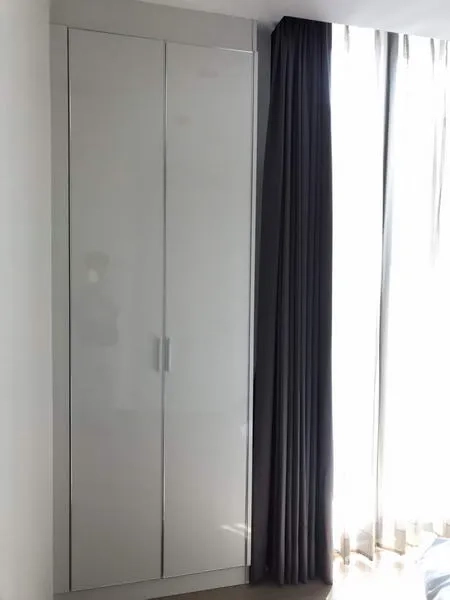 Condominium for rent or sale in Watthana, Bangkok - White built‑in wardrobe beside tall windows with blackout curtains letting in natural light.