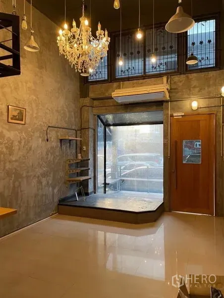 Shophouse for rent in Chatuchak, Bangkok - Front retail area with large glass display window, air conditioner and wooden door beneath a chandelier.
