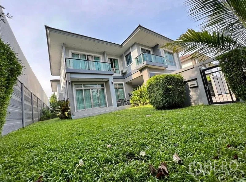 Detached House for rent or sale in Saphan Sung, Bangkok - Front yard view of the detached house with manicured hedges and a metal gate.