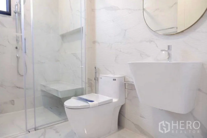 Detached House for sale in Saphan Sung, Bangkok - Modern shower room with glass enclosure, wall-mounted basin and toilet.
