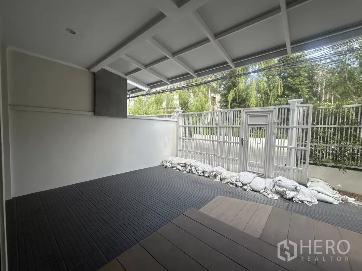 Townhouse for rent in Watthana, Bangkok - Covered carport or terrace with tiled floor and secure front gate.