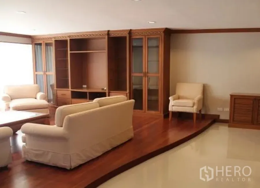 Condominium for rent in Watthana, Bangkok - Spacious living room with cream sofas, raised wooden floor and built-in display cabinets at D.S. Tower 2 condo in Phrom Phong.