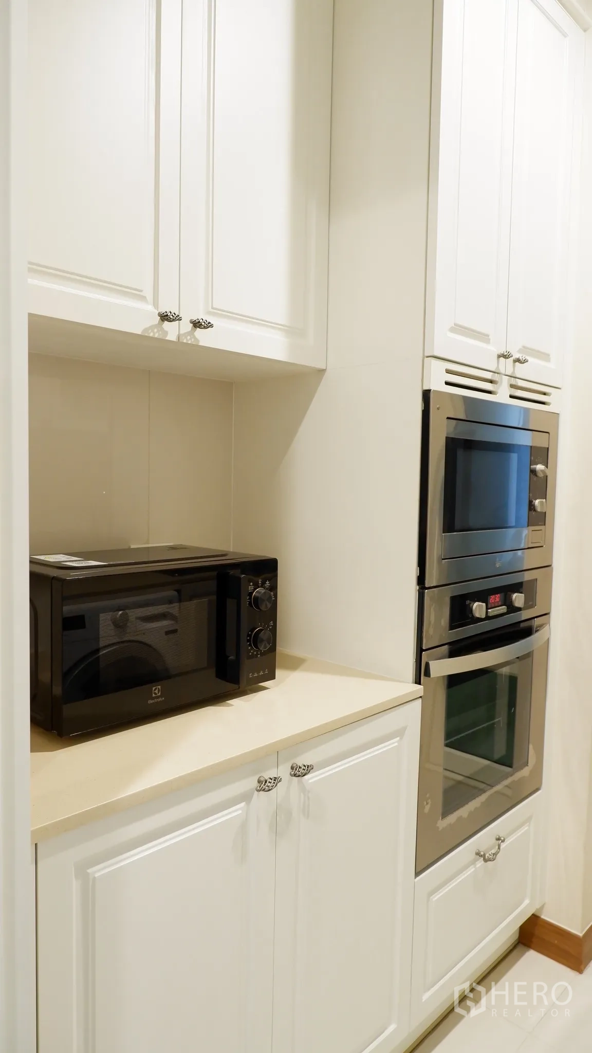 Condominium for rent in Watthana, Bangkok - Compact kitchen corner with built-in microwave and stacked ovens within white cabinetry.
