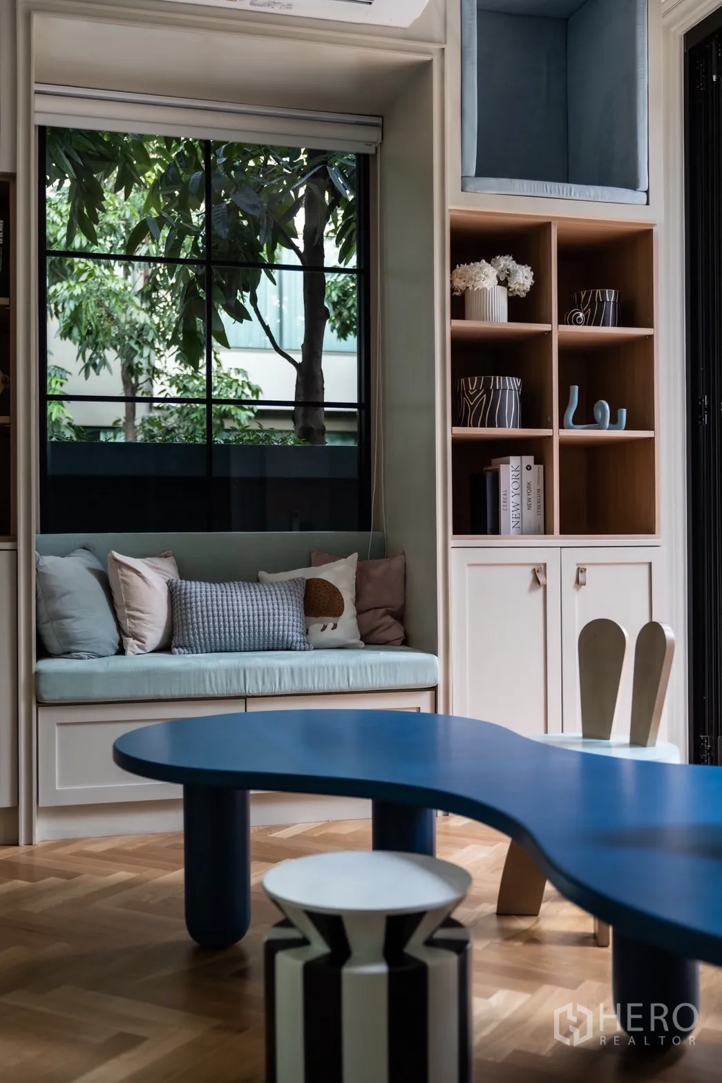 บ้าน ให้เช่าหรือขายในPhra Khanong, Bangkok - มุมนั่งริมหน้าต่างพร้อมหมอนอิง ตู้โชว์ และโต๊ะสีน้ำเงินดีไซน์โค้ง
