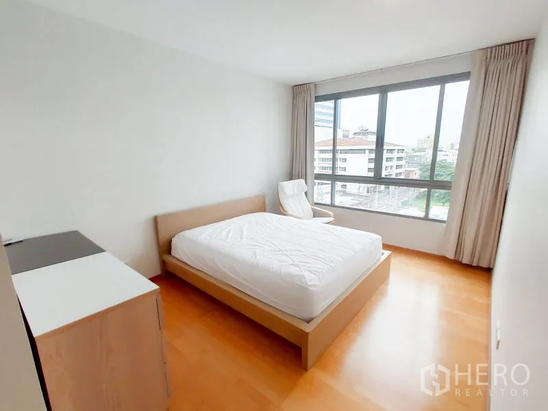 คอนโด ให้เช่าในKhlong Toei, Bangkok - ห้องนอนมาสเตอร์รับแสงดี มุมมองเมืองผ่านหน้าต่างกว้าง พร้อมเก้าอี้พักผ่อน