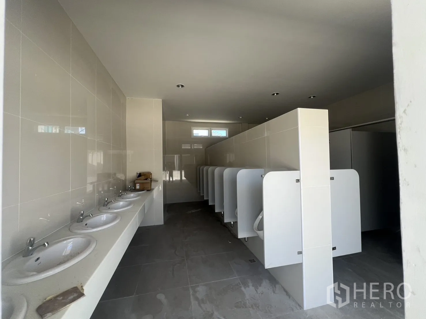 Warehouse for rent in Min Buri, Bangkok - Bright restroom featuring sinks, urinals, and cubicles in an industrial facility.