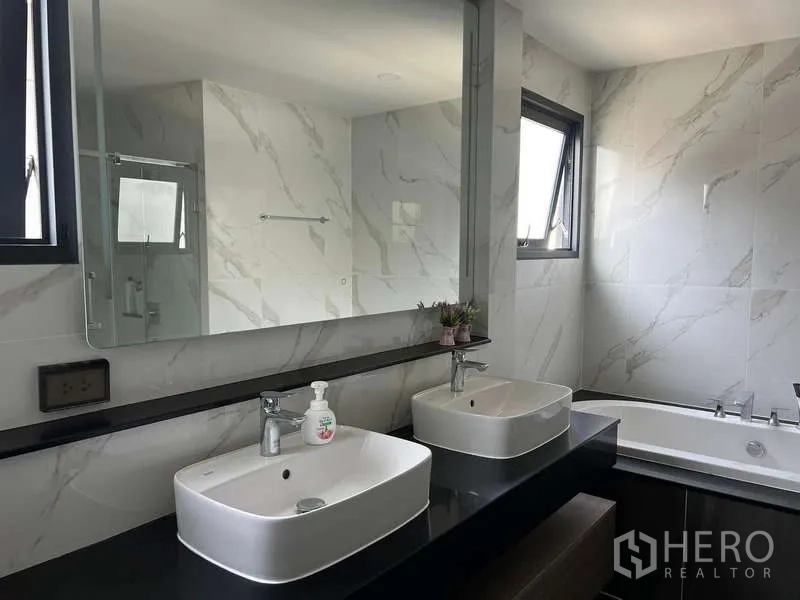 Detached House for rent in Bang Phli, Samut Prakan - Marble-clad bathroom featuring double vanity, large mirror and bathtub.