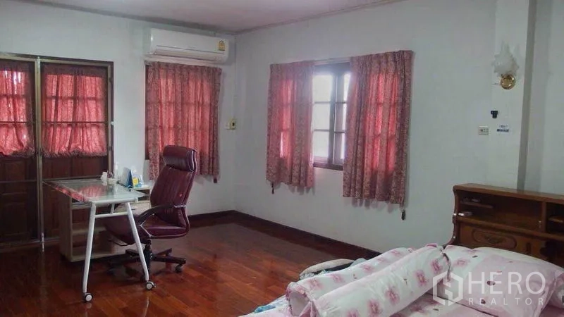 Detached House for sale in Taling Chan, Bangkok - Spacious bedroom with wood floors, glass desk and multiple windows.