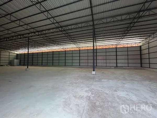 Warehouse for rent in Khlong Toei, Bangkok - Clear-span warehouse interior showing steel columns, ribbed metal roof and open floor area.
