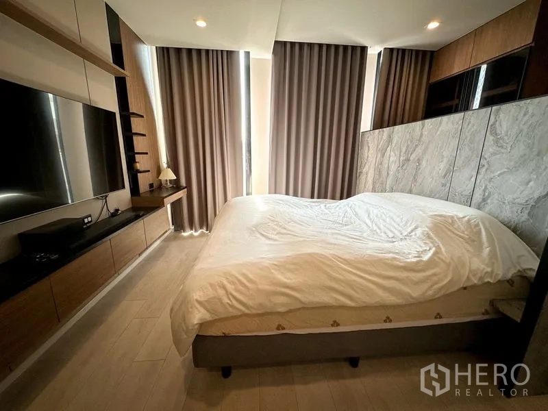 คอนโด ให้เช่าในPathum Wan, Bangkok - ห้องนอนพร้อมเตียงขนาดใหญ่ หัวเตียงลายหินอ่อน และม่านทึบแสง