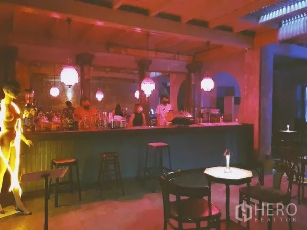 Shophouse for rent in Bang Rak, Bangkok - Moody vintage bar interior with long counter, crystal pendant lights, and rustic concrete walls.