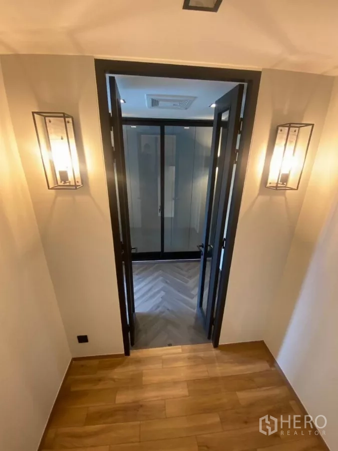 ทาวน์เฮาส์ ให้เช่าในHuai Khwang, Bangkok - โถงทางเดินติดโคมไฟผนัง นำไปสู่ประตูกระจกคู่และห้องพื้นลายก้างปลา.