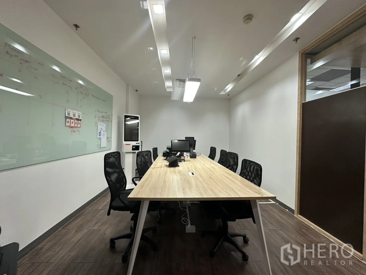 Office Space for rent - Meeting room with long table, mesh chairs, and a glass whiteboard.