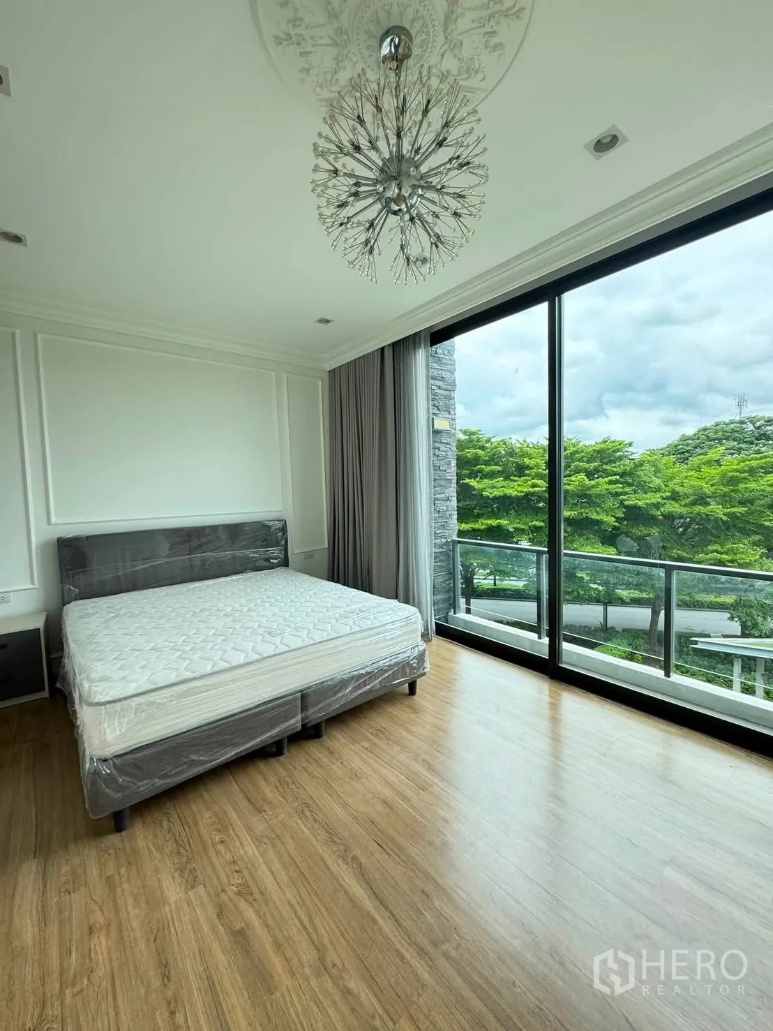 Townhouse for rent in Lat Phrao, Bangkok - Master bedroom with floor-to-ceiling windows, balcony and garden views.
