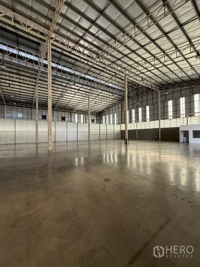 Warehouse for rent in Bang Sue, Bangkok - Far-end interior highlighting clear-span structure, insulated roofing and a small corner office block.