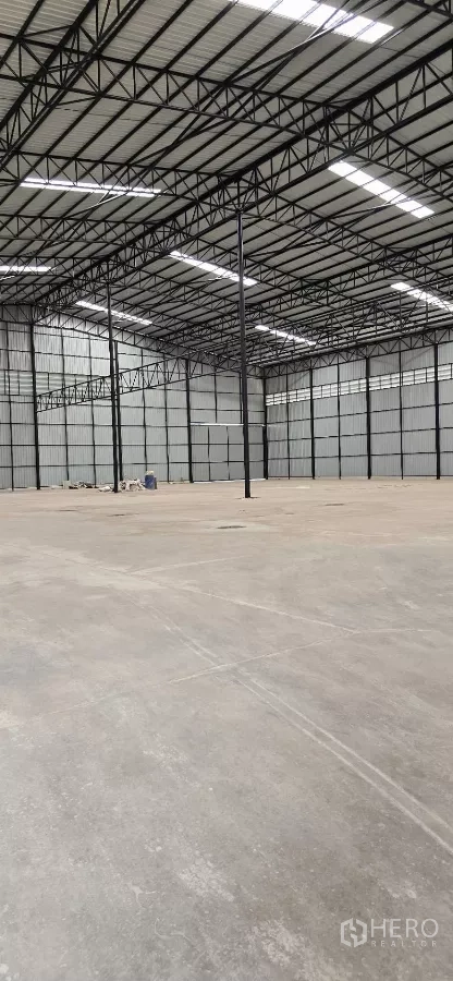 工厂 出租在Mueang Samut Sakhon, Samut Sakhon - 开放式仓库内部，承重混凝土地面与黑色钢框架。