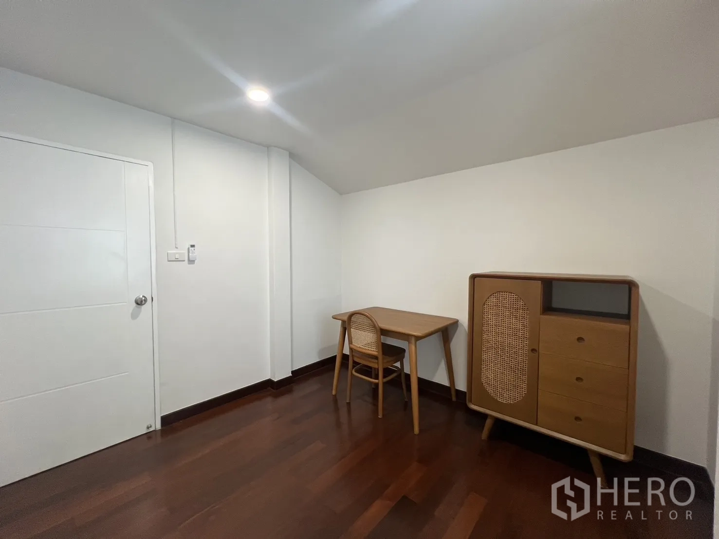 Detached House for rent in Saphan Sung, Bangkok - Study room angle with rattan cabinet and wood flooring.