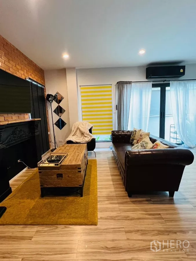 บ้าน ให้เช่าในSaphan Sung, Bangkok - ห้องนั่งเล่นกว้าง โซฟาหนัง ประตูกระจกบานเลื่อน และพื้นไม้.